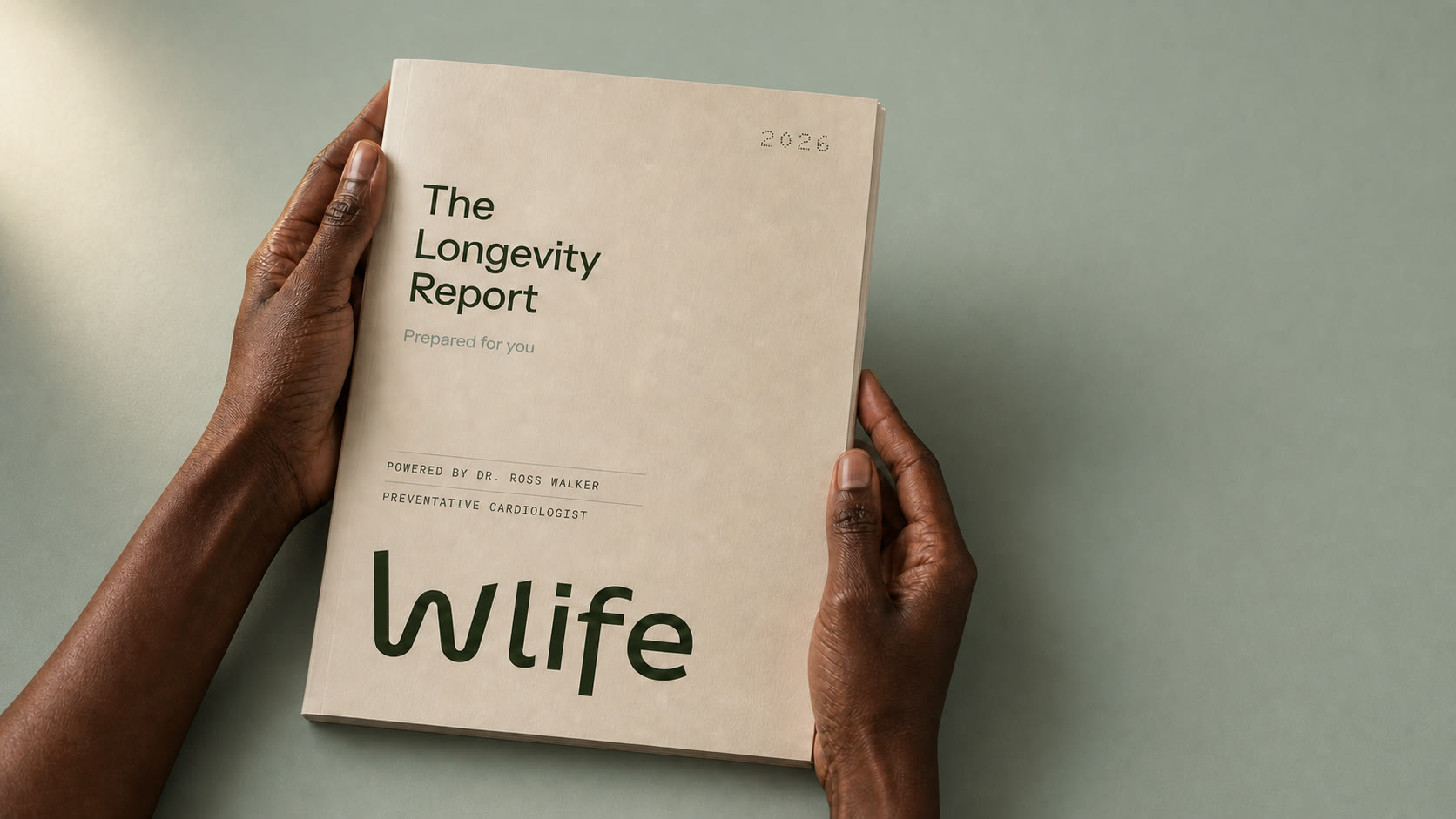 The printed Longevity Report held in two hands over a sage table